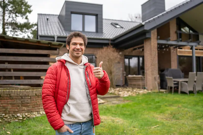Zufriedener Kunde zeigt den Daumen hoch vor seinem sanierten Haus
