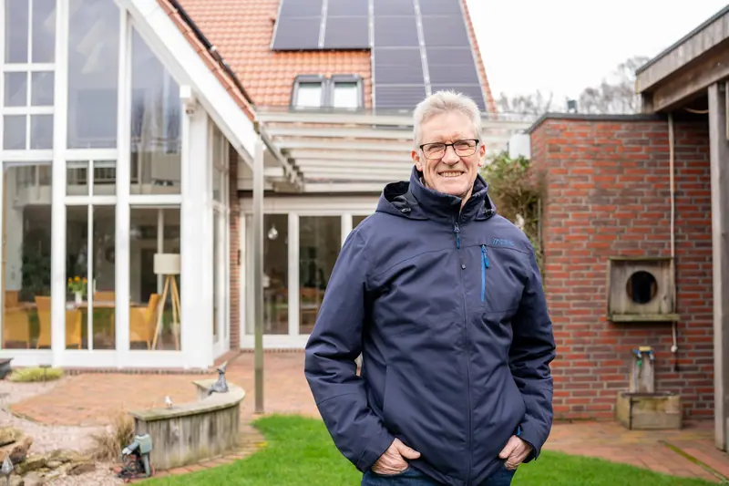 Zufriedener Kunde vor seinem Haus mit Wintergarten und Photovoltaik